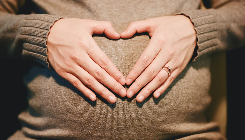Woman making a heart over her pregnant belly