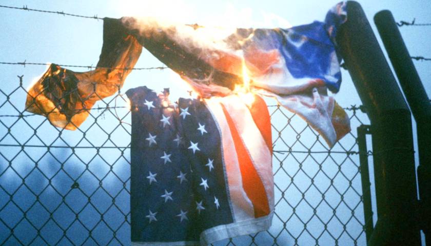 Burning American Flag draped over fence