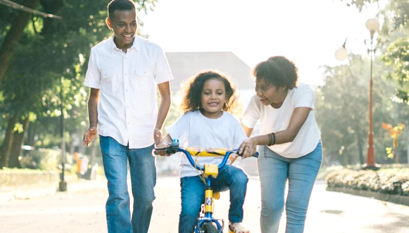 Parents teaching child how to ride a bike